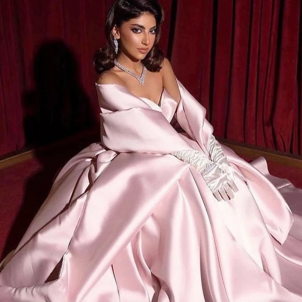 Unleash your daring side with the Robe Amena. This evening dress boasts vintage elegance with ruffled details and a strapless A-line design. Its pink hue adds a simple touch while the gloves add a bold statement. Perfect for formal occasions and prom, this dress will make you stand out in any party.