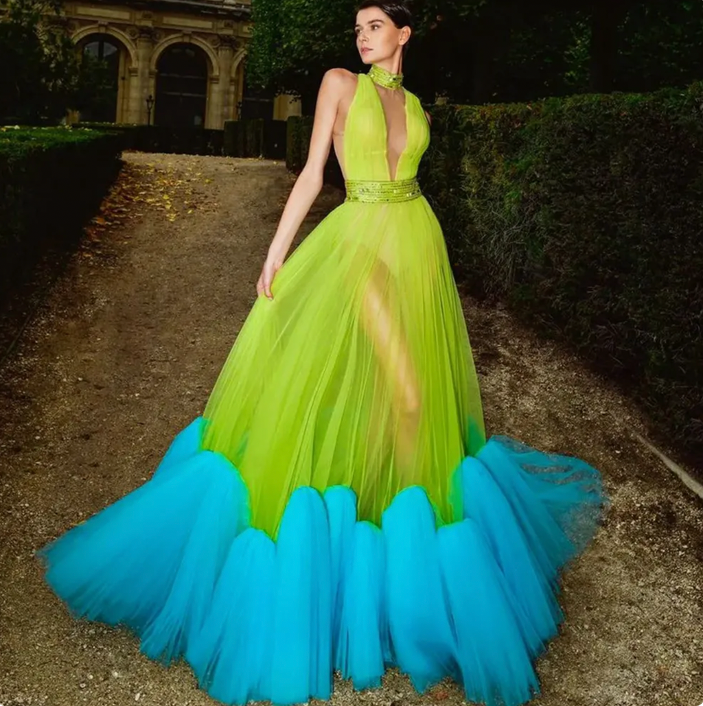 Indulge in the rich elegance of our Dress Alessandra. Custom colors and intricate beadwork adorn the layered tulle fabric, giving this dress a lush and extra puffy silhouette. The back features a floral applique, adding a touch of femininity to this stunning prom gown. Be the center of attention in this neon green blue masterpiece.
