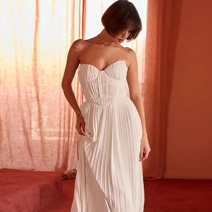 The Dress Amorata features an elegant solid design with pleated details and a strapless neckline, ideal for formal occasions. It also has an off-shoulder and backless design, adding a stylish touch. The long length and sleeveless feature make it a perfect choice for any season. Elevate your wardrobe with this stunning dress.