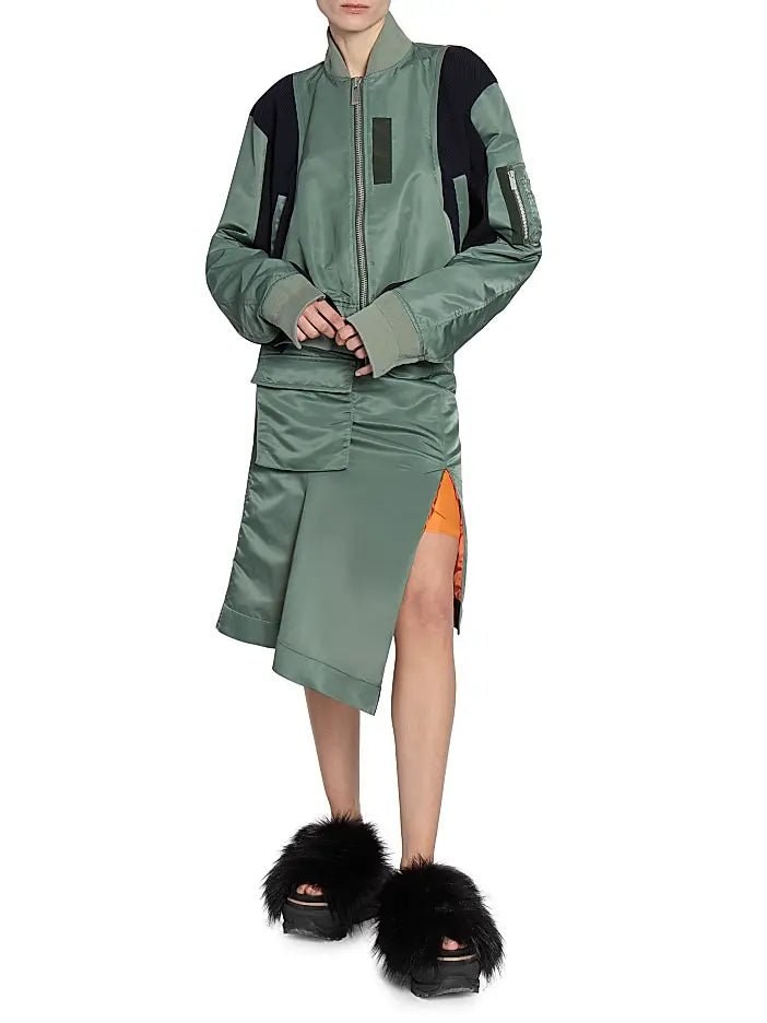 This Nylon Twill Knit Bomber Jacket from Sacai features inset ribbed panels that create a unique striped texture, enhancing its modern cropped blouson silhouette. Designed with a ribbed stand collar and snap cuffs, it combines style with comfort. Practical chest, side, and sleeve zip pockets offer secure storage, while the back vent ensures ease of movement. A two-way front zip closure completes this versatile piece, perfect for elevating your wardrobe with a distinctive, fashion-forward edge.