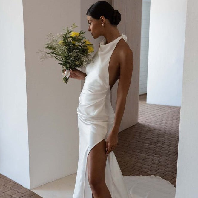 Dress Goldie is the perfect choice for modern brides. Featuring a stunning halter neckline and sleeveless design, this simple mermaid wedding dress is made of high-quality satin material and boasts an open back and high side slit for added elegance. With its floor length, it's sure to make a lasting impression on your special day.