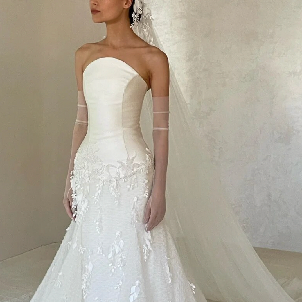 This elegant lace trumpet strapless dress, known as Dress Remie, features delicate lace appliques that add a touch of sophistication to your wedding day look. Made with expert craftsmanship, this dress exudes elegance and charm, perfect for the modern bride looking for a timeless and refined look.
