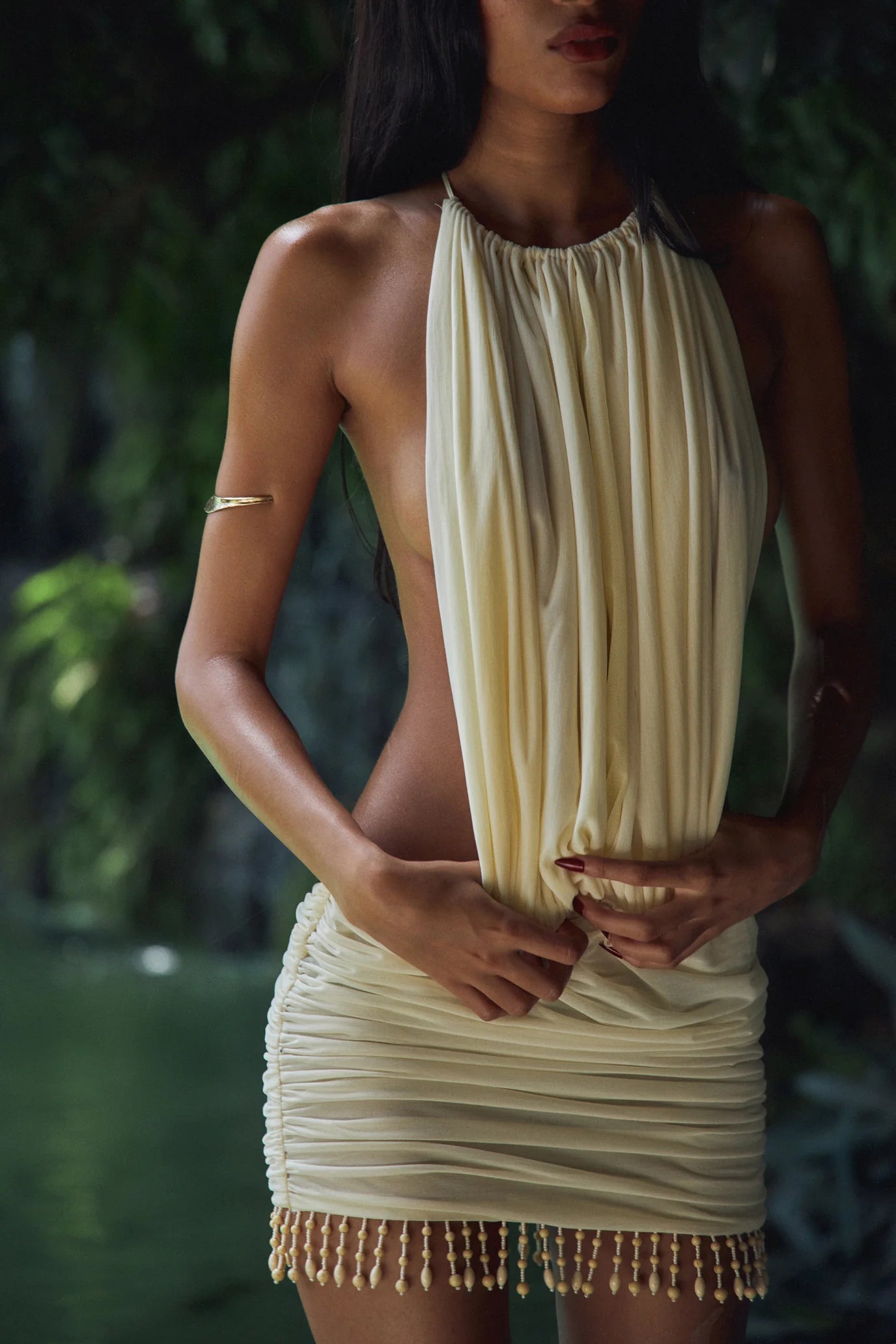 The La Piscine Mini Dress in Butter blends elegance with versatility. Its draped, ruched design and semi-sheer fabric create a delicate silhouette, while adjustable front panels ensure a perfect fit. The open back and hand-beaded hem add refined detail, and the unique ties can be styled as a halter or strapless, offering multiple chic looks for any occasion. Embrace effortless sophistication with this captivating mini dress.