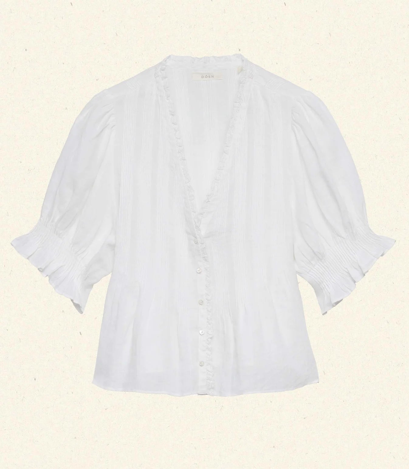Experience timeless elegance with the Karlie Top, crafted from lightweight ramie for a delicate, airy feel. Its plunging V-neckline framed by soft ruffles and intricate pintuck detailing adds a touch of vintage charm. The starburst button line down the front enhances its refined look, while short puffed sleeves bring a playful silhouette. Perfect for wearing loose or tucked into high-waisted jeans, this versatile top effortlessly elevates any outfit with a graceful Edwardian-inspired style.