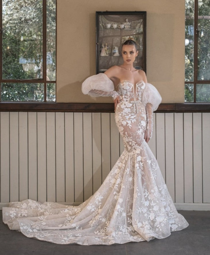 Indulge in the enchanting elegance of the Robe Magda. This stunning dress boasts intricate lace and embroidered flowers adorned with sparkling crystal beading. Its detachable off-the-shoulder puff tulle sleeves add a touch of versatility, while the iconic Berta Bow Belt adds a touch of luxury. Perfect for any special occasion.