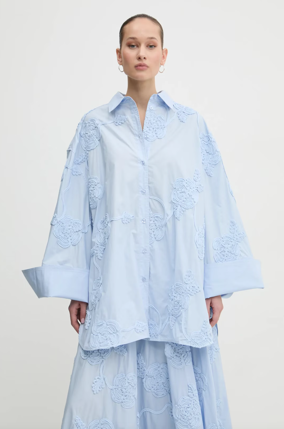 Elevate your style with this high-waisted maxi skirt crafted from sustainable organic cotton. Its flowing, flared design moves gracefully, enhanced by delicate tonal floral embroidery that adds elegant texture. With carefully tailored gathering at the waistband and a hidden side zipper, it offers a flattering fit and lasting comfort. Ideal for sophisticated events, this skirt combines refined elegance with eco-conscious craftsmanship to enhance your wardrobe effortlessly.