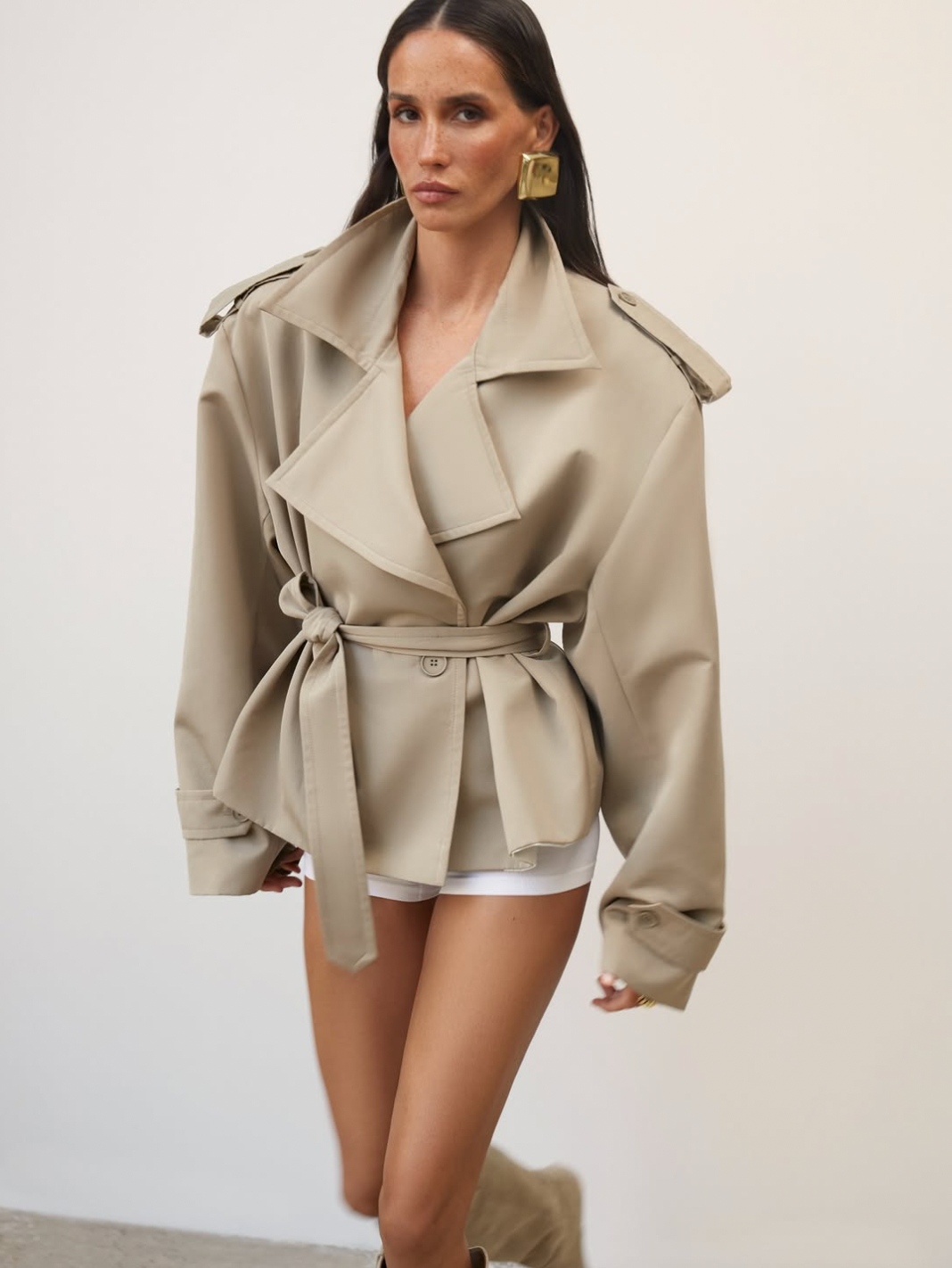 Elevate your wardrobe with this cropped beige trench coat, designed to blend timeless elegance with modern style. Its tailored fit effortlessly complements any outfit, while the neutral beige tone adds versatile sophistication. Ideal for layering, this coat offers both comfort and a chic silhouette, making it a must-have piece for your collection.