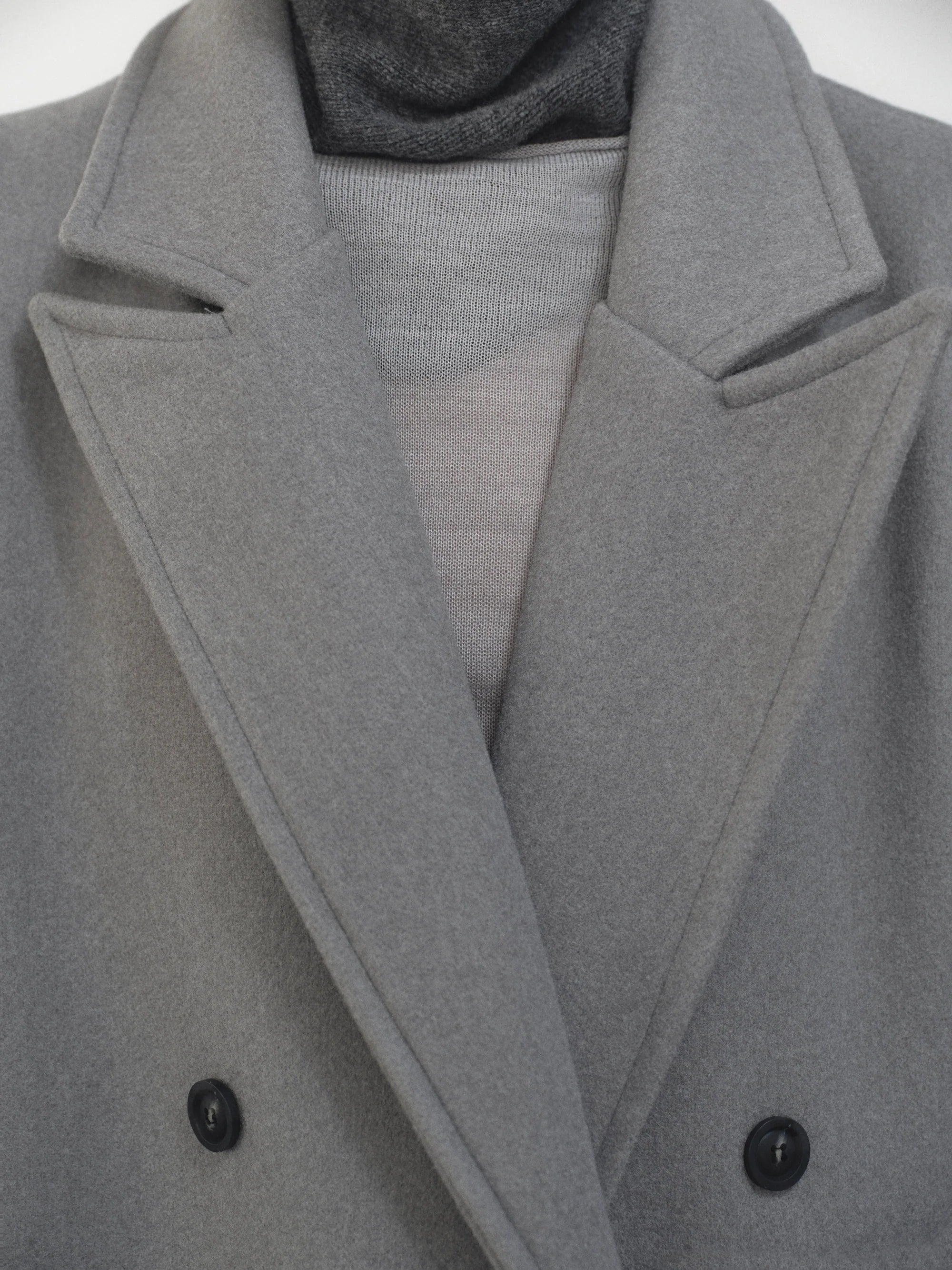 Embrace effortless sophistication with the Wallis Oversized Grandpa Coat, a contemporary take on timeless tailoring. Crafted from mid-weight bonded wool-blend fabric, this unisex piece features a dramatically oversized silhouette that commands attention. The striking long peak lapels and double-breasted closure create architectural interest, while structured shoulder pads deliver modern edge. 