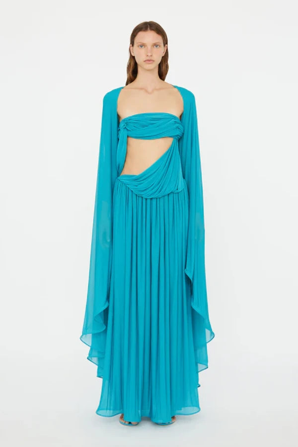 Elevate your wardrobe with the Gyre Cape Effect Dress by Christopher Esber. Crafted from soft jersey, this vibrant turquoise maxi features a dramatic cape-effect overlay and a sleek bandeau bodice that flows to the floor, enhancing your silhouette with delicate draping. Designed for those who seek effortless elegance, this dress makes a bold statement at any special event, especially when complemented with silver jewelry for a touch of refined sophistication.