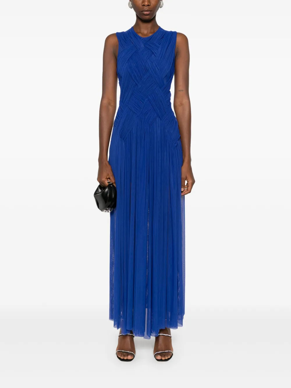 Embrace elegance with the Emotional braided maxi dress by Atu Body Couture. This stunning royal blue creation features intricate braid detailing and gathered accents that flow beautifully across a fully pleated silhouette. The mesh design adds an alluring touch, while the draped crew neck and sleeveless cut offer modern sophistication. The dramatic high-low hem transitions to a floor-length finish, creating movement with every step. 