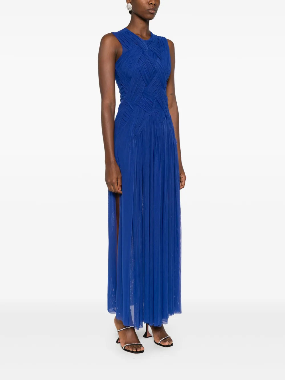 Embrace elegance with the Emotional braided maxi dress by Atu Body Couture. This stunning royal blue creation features intricate braid detailing and gathered accents that flow beautifully across a fully pleated silhouette. The mesh design adds an alluring touch, while the draped crew neck and sleeveless cut offer modern sophistication. The dramatic high-low hem transitions to a floor-length finish, creating movement with every step. 