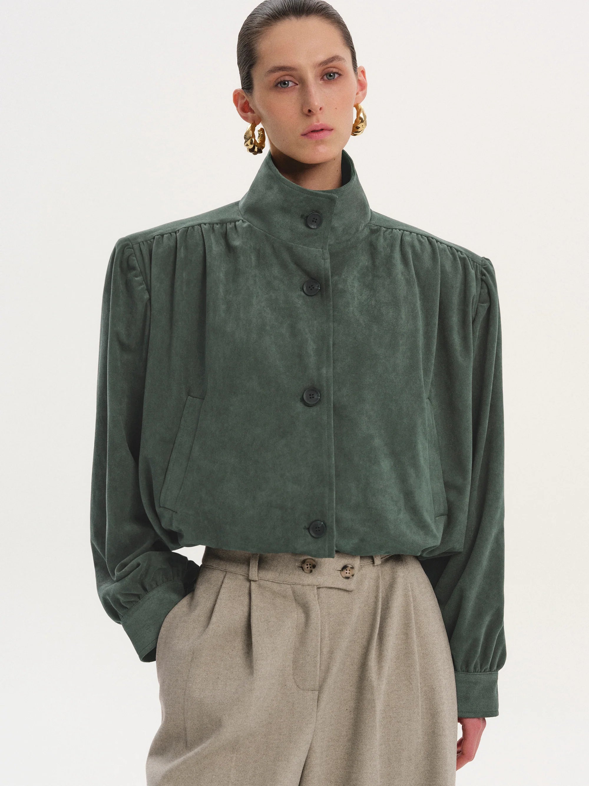 This Ruched Suede Jacket in Grey blends timeless style with contemporary flair. Featuring a boxy silhouette and padded shoulders, it exudes confidence, while the stand collar and gathered pleats add refined detail. The softly structured waistband creates a relaxed blouson effect, offering a polished look that’s both comfortable and stylish. Fully lined for all-day ease, this jacket effortlessly enhances any outfit with understated sophistication.