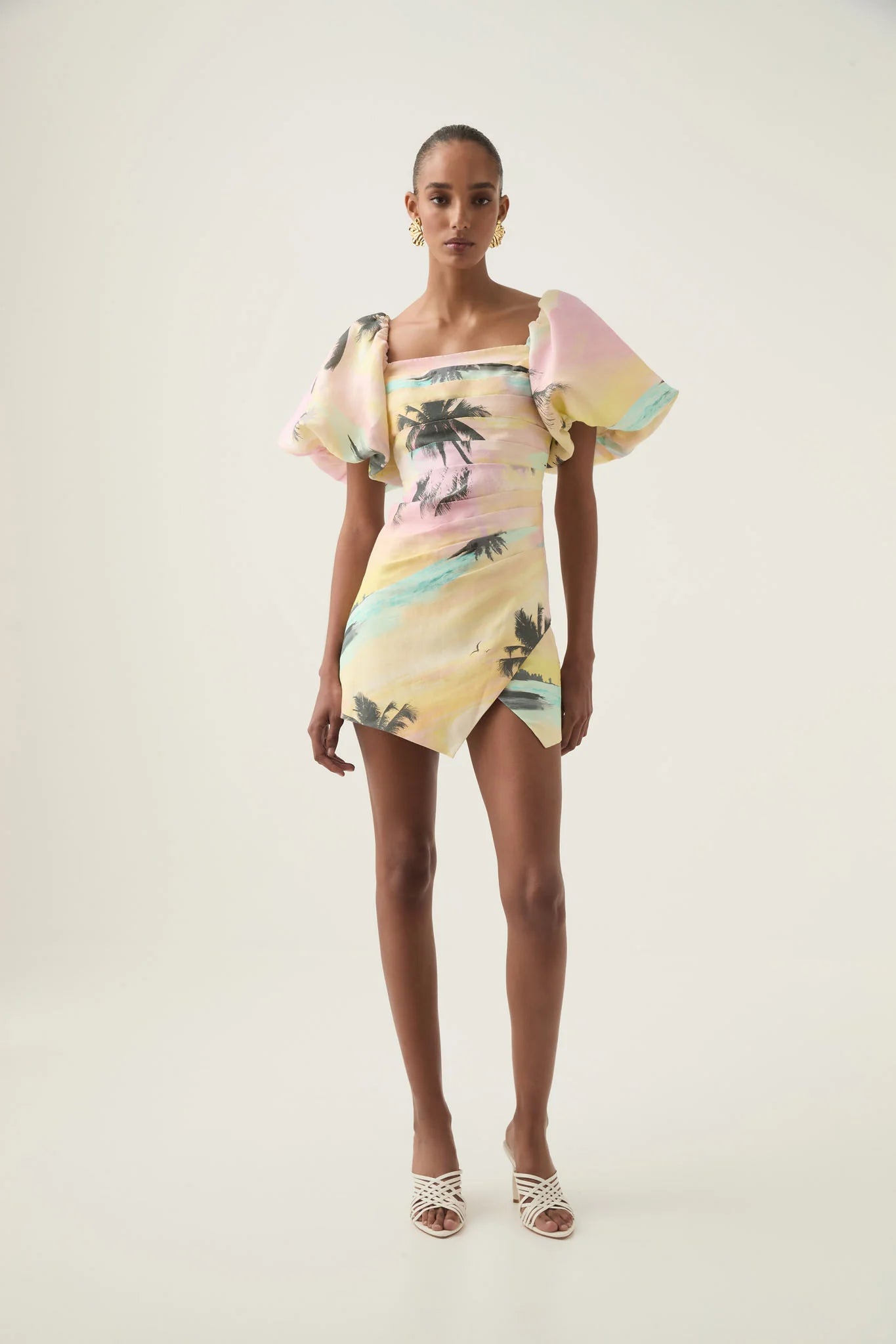 Elevate your style with the Paradise Wrap Front Mini Dress, featuring a flattering straight neckline and playful puff sleeves with stretch cuffs for comfort and charm. The intricate tucked detail adds texture and sophistication, while the angular hem offers a modern silhouette. Fully lined and secured with a zip, hook, and eye closure, this dress combines elegance with ease for any occasion.