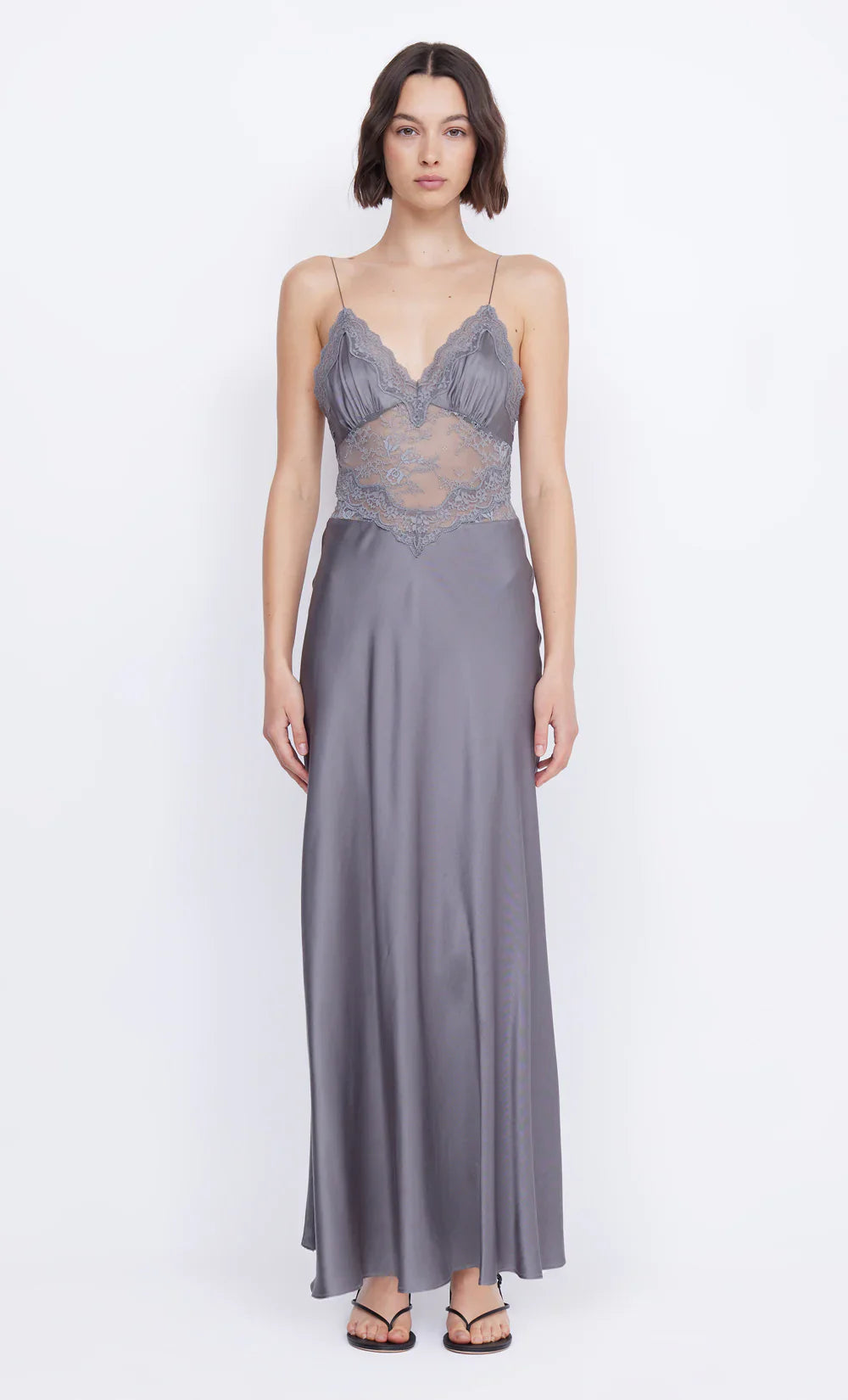 The Amoras Gown by BEC + BRIDGE combines elegance and allure with its V-neckline and flowing maxi silhouette. Crafted with a bias-cut skirt for a flattering fit, this dress features stretch lace that delicately reveals the midsection, adding a subtle hint of sophistication. The gathered bust cups and lace-trimmed neckline enhance its feminine charm, making it the perfect choice for unforgettable events where you want to stand out.