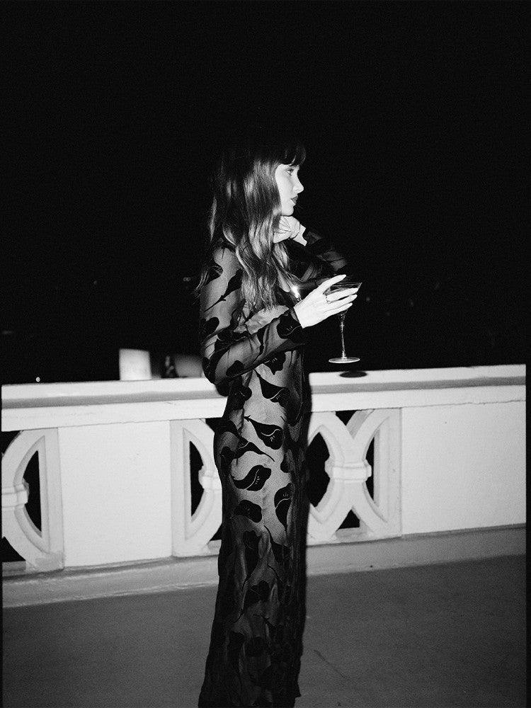 The Inka Dress in Falling Lily Devore combines elegance and subtle allure with its long, semi-sheer design that offers just the right amount of coverage. Featuring a deep neckline and a bias-cut skirt, it captures the ethereal grace of Kate Bush and the bohemian spirit of Joni Mitchell. Ideal for cooler summer nights, this dress pairs beautifully with sky-high heels to create a look of effortless, sexy femininity.