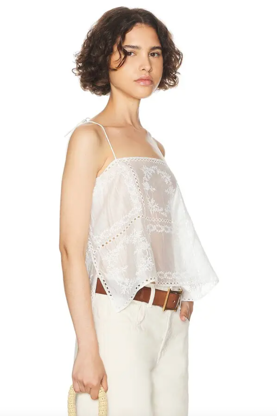 Introducing the Handkerchief Camisole by Helsa, crafted from luxurious linen and adorned with delicate eyelets and embroidered florals. The shoulder strap tie closures and side slits add a touch of sophistication. Perfect for warm weather, this garment is purposefully sheer, adding an alluring touch. Don't be afraid to let your undergarments peek through. Elevate your wardrobe with this elegant piece.