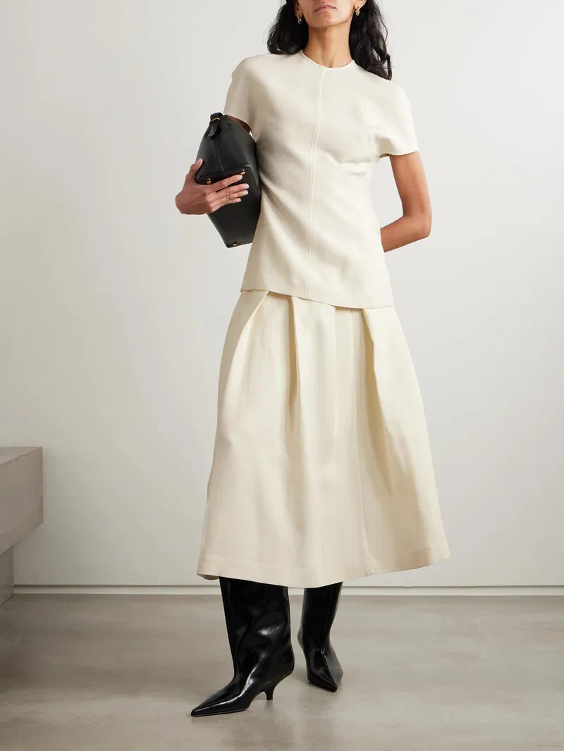 This versatile midi skirt combines timeless elegance with everyday wearability. Crafted from a luxurious wool and silk blend, it features deep pleats that create beautiful movement and dimension with every step. The refined design pairs effortlessly with knee boots, mules, or your favorite footwear, making it a wardrobe essential that transitions seamlessly from season to season. Invest in a piece that works as hard as you do.