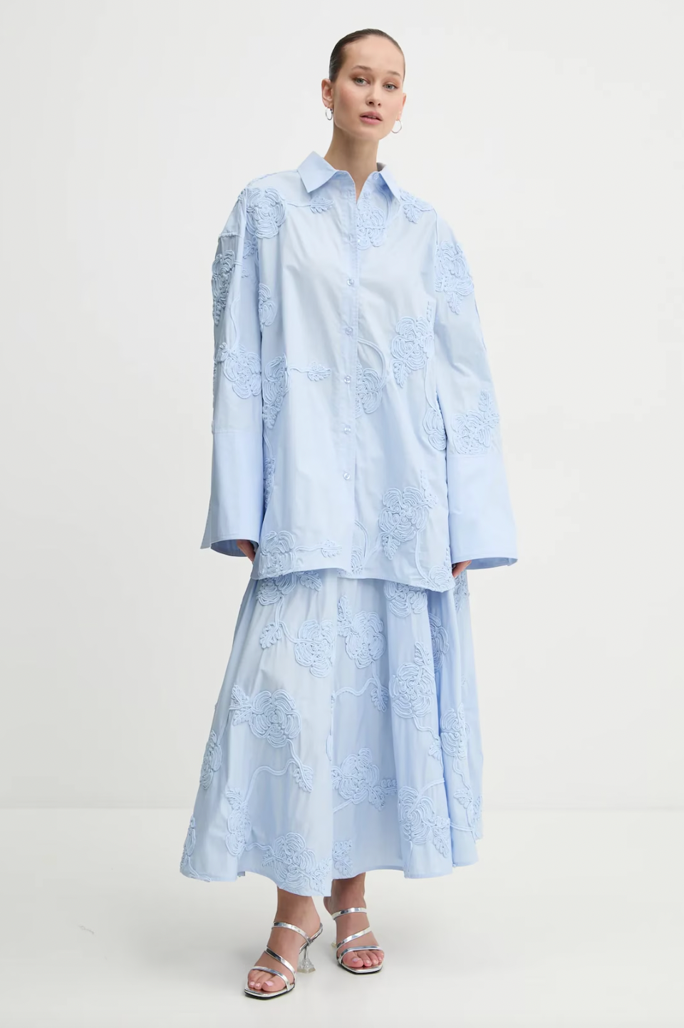 Elevate your style with this high-waisted maxi skirt crafted from sustainable organic cotton. Its flowing, flared design moves gracefully, enhanced by delicate tonal floral embroidery that adds elegant texture. With carefully tailored gathering at the waistband and a hidden side zipper, it offers a flattering fit and lasting comfort. Ideal for sophisticated events, this skirt combines refined elegance with eco-conscious craftsmanship to enhance your wardrobe effortlessly.