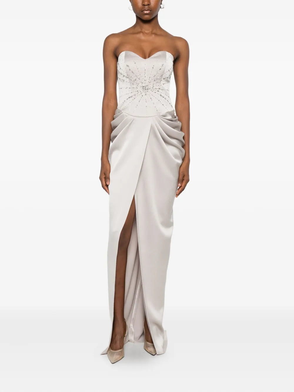 The Fabiana dress by M.Marquise is an imported evening gown that commands attention. This strapless masterpiece features elegant draped detailing and cascades to a dramatic floor length, creating an effortlessly sophisticated silhouette. Shimmering silver-tone crystal embellishments catch the light with every movement, adding glamorous sparkle to your most memorable moments. Perfect for galas, weddings, or upscale celebrations where timeless elegance matters.