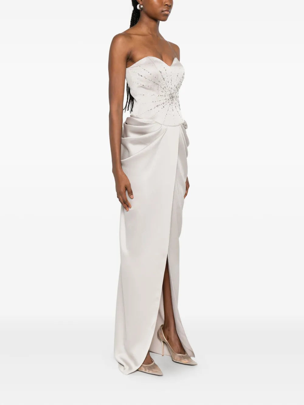 The Fabiana dress by M.Marquise is an imported evening gown that commands attention. This strapless masterpiece features elegant draped detailing and cascades to a dramatic floor length, creating an effortlessly sophisticated silhouette. Shimmering silver-tone crystal embellishments catch the light with every movement, adding glamorous sparkle to your most memorable moments. Perfect for galas, weddings, or upscale celebrations where timeless elegance matters.