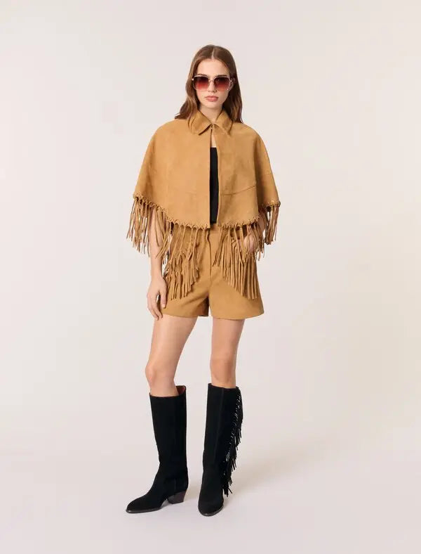 This Short Leather Fringed Cape by Maje combines the luxurious texture of suede with a striking cape design, featuring delicate fringed edges and polished silver eyelets for an edgy yet elegant look. Its classic shirt collar and secure hook-and-eye fastening ensure both style and comfort, making it a standout piece that elevates any outfit with effortless sophistication.