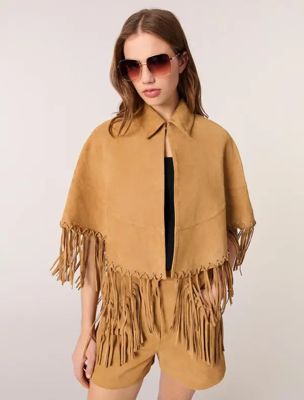 This Short Leather Fringed Cape by Maje combines the luxurious texture of suede with a striking cape design, featuring delicate fringed edges and polished silver eyelets for an edgy yet elegant look. Its classic shirt collar and secure hook-and-eye fastening ensure both style and comfort, making it a standout piece that elevates any outfit with effortless sophistication.