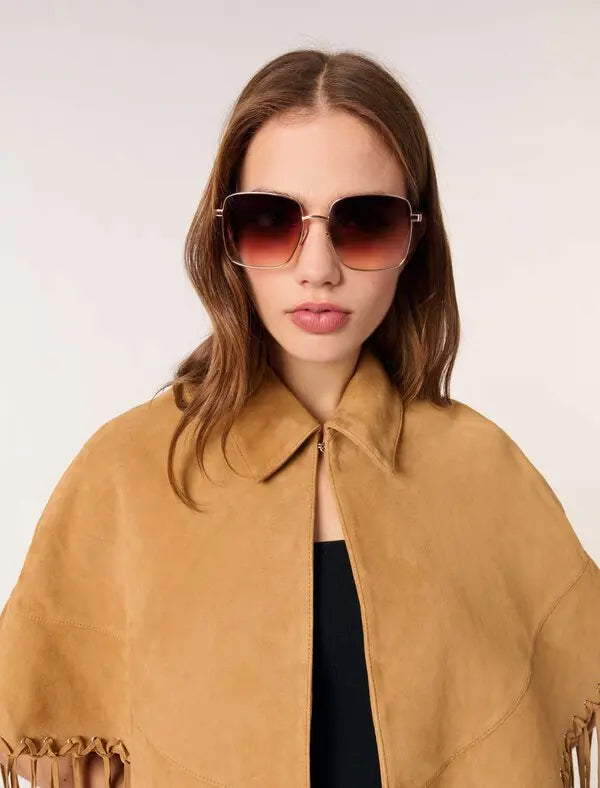 This Short Leather Fringed Cape by Maje combines the luxurious texture of suede with a striking cape design, featuring delicate fringed edges and polished silver eyelets for an edgy yet elegant look. Its classic shirt collar and secure hook-and-eye fastening ensure both style and comfort, making it a standout piece that elevates any outfit with effortless sophistication.
