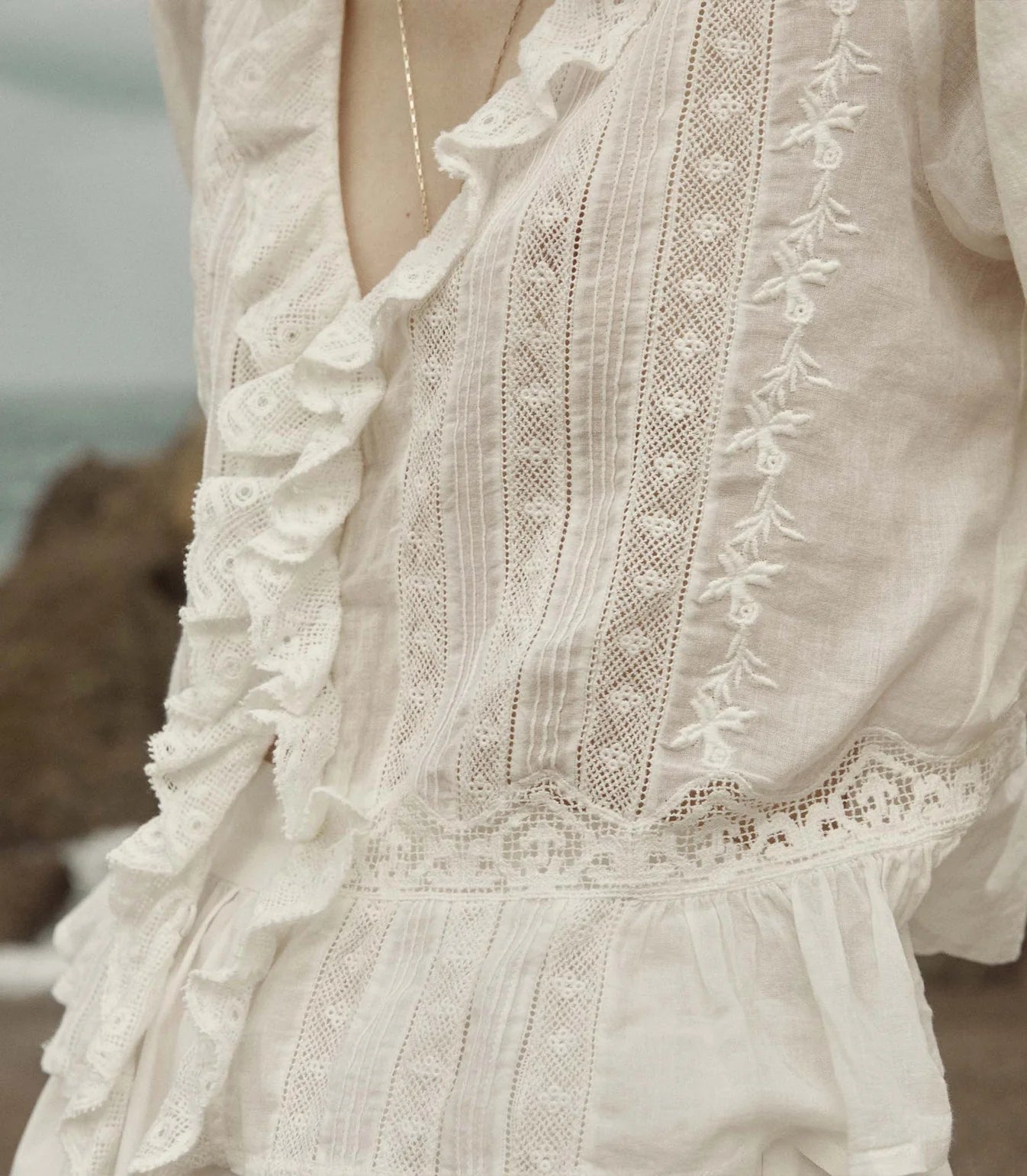 Crafted from the softest organic cotton voile, the Victorian-inspired Eldoris Top features a plunging V-neckline framed with cascading lace-trimmed ruffles that extend down the bodice and alternating panels of inset lace, clustered pintucks, and intricate embroidery at the yoke and back. A line of delicate buttons run down the front, while a cinched and slightly cropped waist finishes in a subtle peplum.