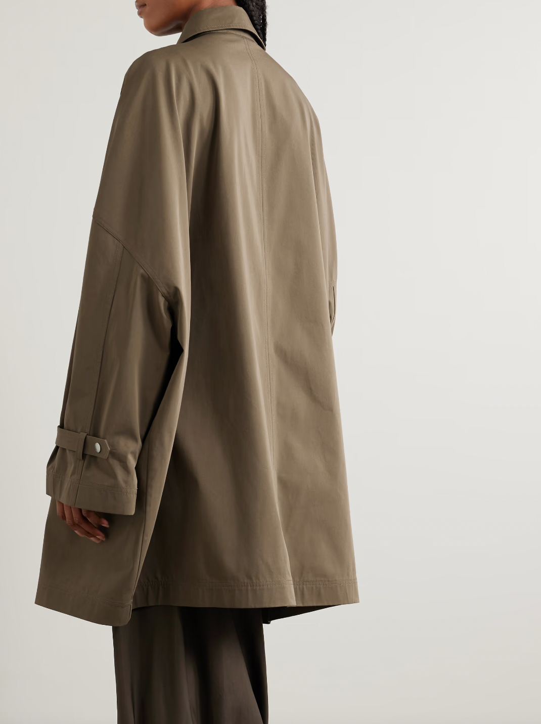 This organic cotton trench coat from TOTEME elevates any outfit with its clean, structured silhouette. Crafted from crisp organic cotton, it offers comfort and sustainability. Its roomy shape ensures ease of movement, while cuff tabs and a throat latch beneath the collar add thoughtful detailing. The partially concealed placket creates a sleek, polished look, making this coat a versatile essential for refined style.