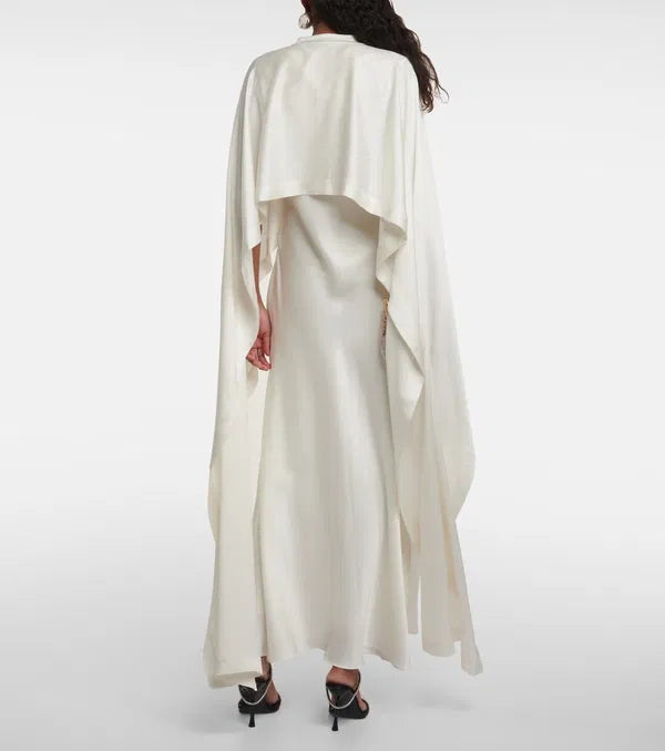 Sparkle and shine in the Amory Caped Gown by Simkhai. This bridal gown features intricate lace work, architectural silhouette, and luxurious materials for effortless chic and sophistication on your special day. Designed to flatter and accentuate the female form, it's the perfect choice for any bride looking for quality and craftsmanship.