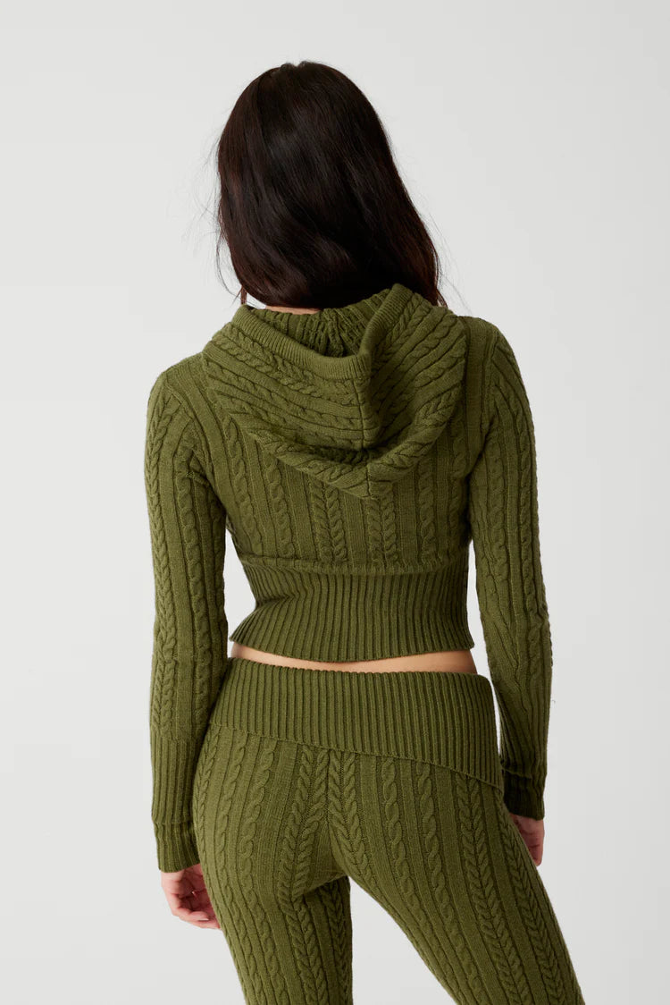 The Aimee Cloud Knit Hoodie by Frankies Bikinis is designed with the signature cable cloud knit fabric to provide body sculpting and warmth. It features vintage-inspired hardware and trim, ribbing on the cuffs and waist, a zip up front, and our new shade of Jade Green.