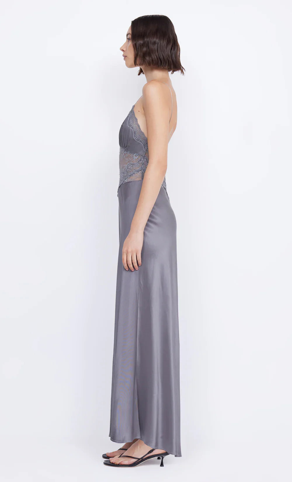 The Amoras Gown by BEC + BRIDGE combines elegance and allure with its V-neckline and flowing maxi silhouette. Crafted with a bias-cut skirt for a flattering fit, this dress features stretch lace that delicately reveals the midsection, adding a subtle hint of sophistication. The gathered bust cups and lace-trimmed neckline enhance its feminine charm, making it the perfect choice for unforgettable events where you want to stand out.