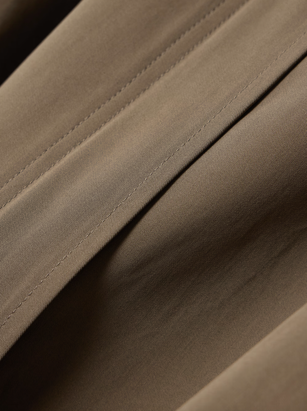 This organic cotton trench coat from TOTEME elevates any outfit with its clean, structured silhouette. Crafted from crisp organic cotton, it offers comfort and sustainability. Its roomy shape ensures ease of movement, while cuff tabs and a throat latch beneath the collar add thoughtful detailing. The partially concealed placket creates a sleek, polished look, making this coat a versatile essential for refined style.