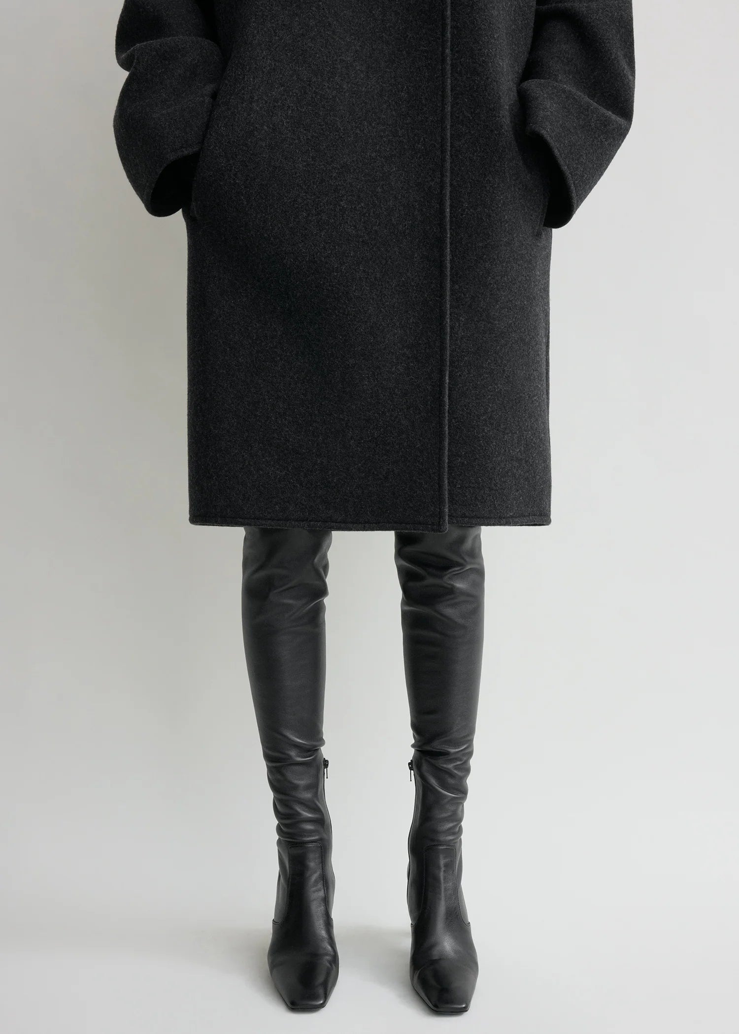 Effortless sophistication meets architectural design in this collarless felt coat by Toteme. Crafted from substantial wool-blend felt, its clean lines and drop shoulders create a modern silhouette that drapes like a protective shell around your frame. The buttonless double-breasted front eliminates fussy closures, while jet pockets offer practical elegance. Partial interior lining and an internal pocket balance minimalist aesthetics with everyday functionality. 