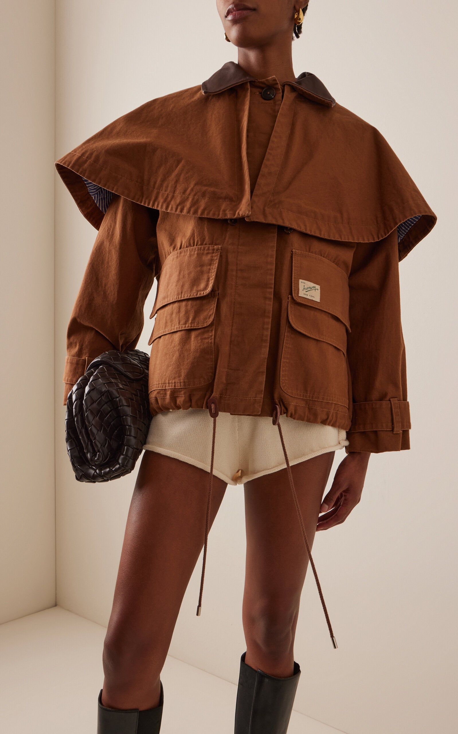 Embrace effortless sophistication with the Carolyn Cape-Detailed Cotton Workwear Jacket by SEA NY. This statement piece combines utilitarian charm with unexpected elegance, featuring a structured oversized silhouette crafted from crisp cotton canvas. The signature flouncy capelet adds a playful twist to classic workwear styling, making it perfect for elevating everyday looks or creating bold, fashion-forward outfits. 