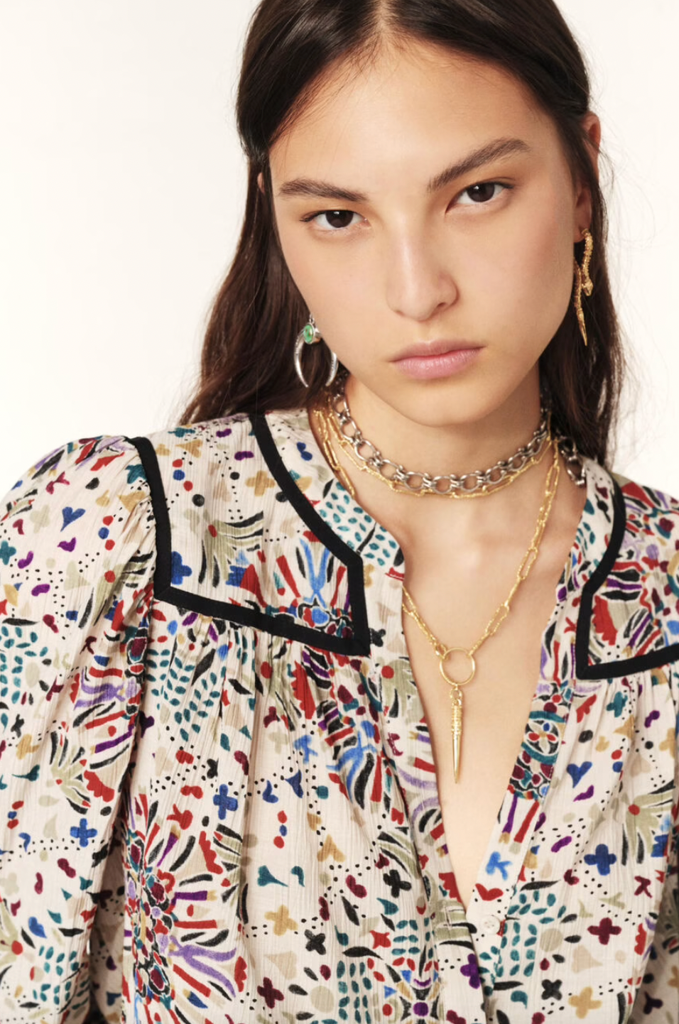 Indulge in the luxurious Faizae Blouse by ba&sh, a straight-cut shirt that highlights your figure with its fitted shoulders and loose, stretchy style. The small round collar and V-neck add a touch of sophistication, while the slightly puffed sleeves and contrasting bias details elevate the flowing fabric with a graphic motif. Perfect for the working girl with a taste for high fashion.