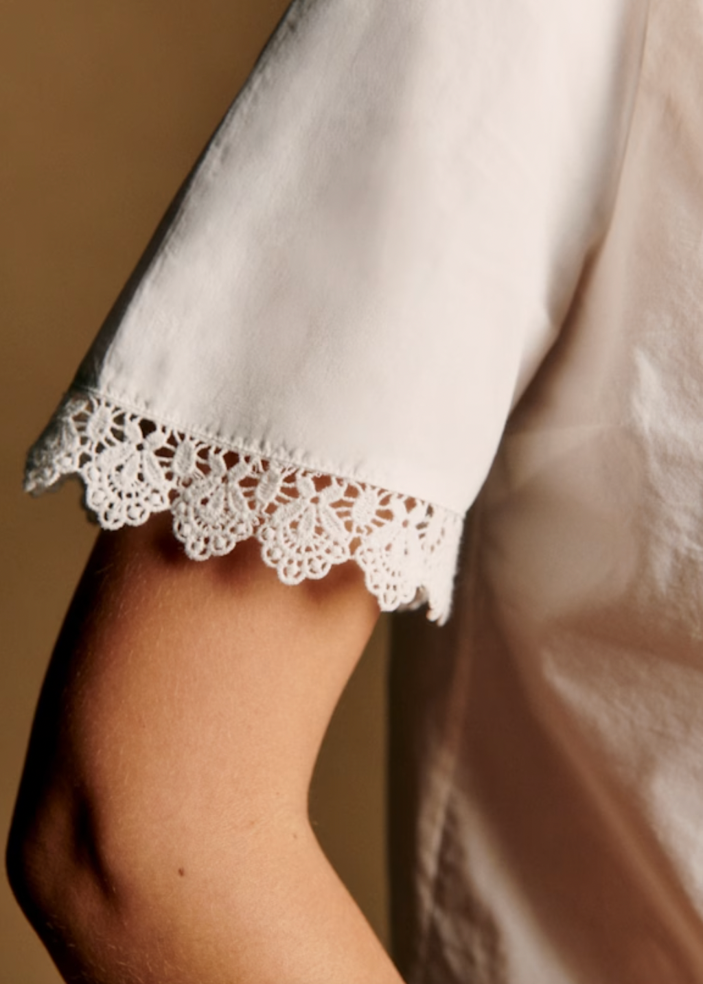 The Eponia Shirt combines timeless elegance with contemporary style. This cropped short-sleeve design features delicate openwork embroidery across the front and button placket, while gathered shoulders add subtle dimension. Lace band inserts frame the round neckline and cuffs for an refined finish, complemented by lustrous mother-of-pearl buttons. Perfect for layering or wearing solo, this piece effortlessly elevates any wardrobe with its intricate detailing and flattering silhouette.