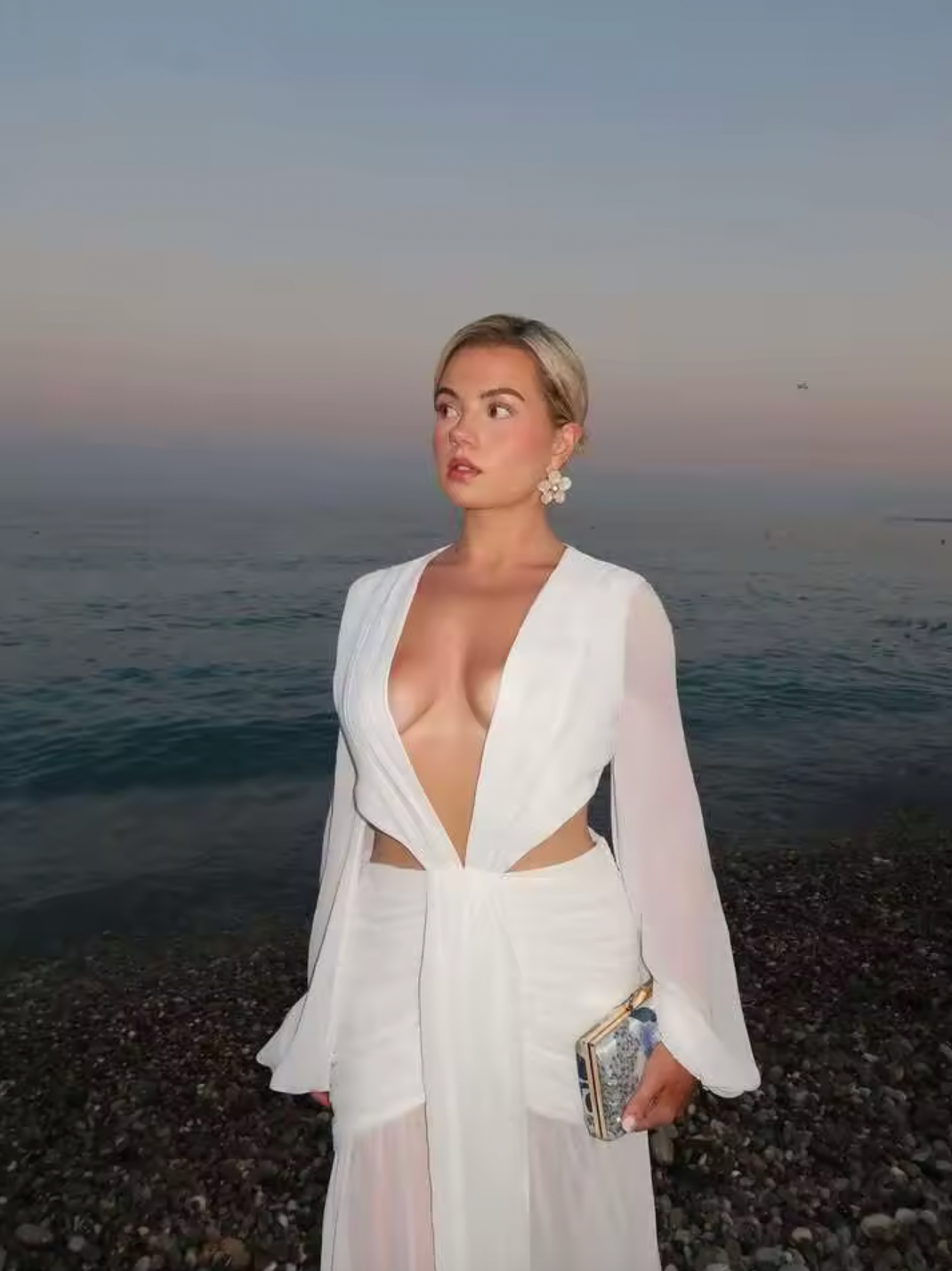 The Andrina Maxi Dress is a stunning statement piece that combines romance with modern elegance. Crafted from delicate chiffon, this maxi features long, sheer blouson sleeves and a daring deep plunge neckline that exudes confidence. The open lace-up back with adjustable ties allows you to customize your fit while showcasing an alluring silhouette. 