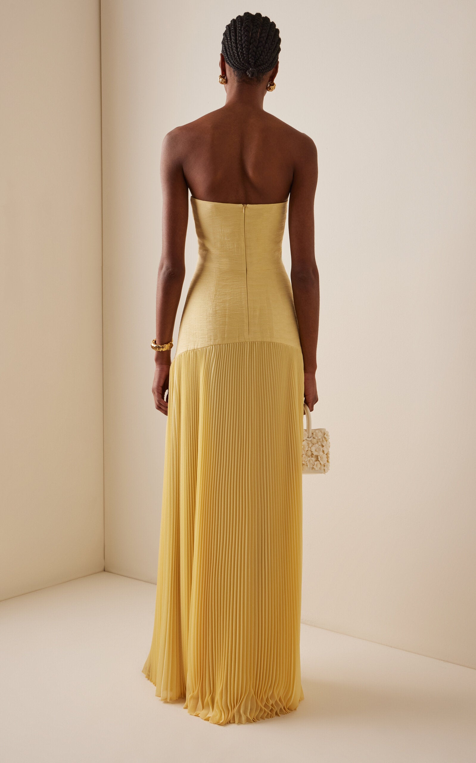 The Sunniva Dress showcases a fitted strapless bodice with a graceful curved dropped waist, seamlessly flowing into a delicate plisse skirt. Its elegant silhouette highlights your figure while offering effortless movement. Pair it with bold statement earrings to complete a look that embodies refined sophistication and modern style. Perfect for making a lasting impression at any event.