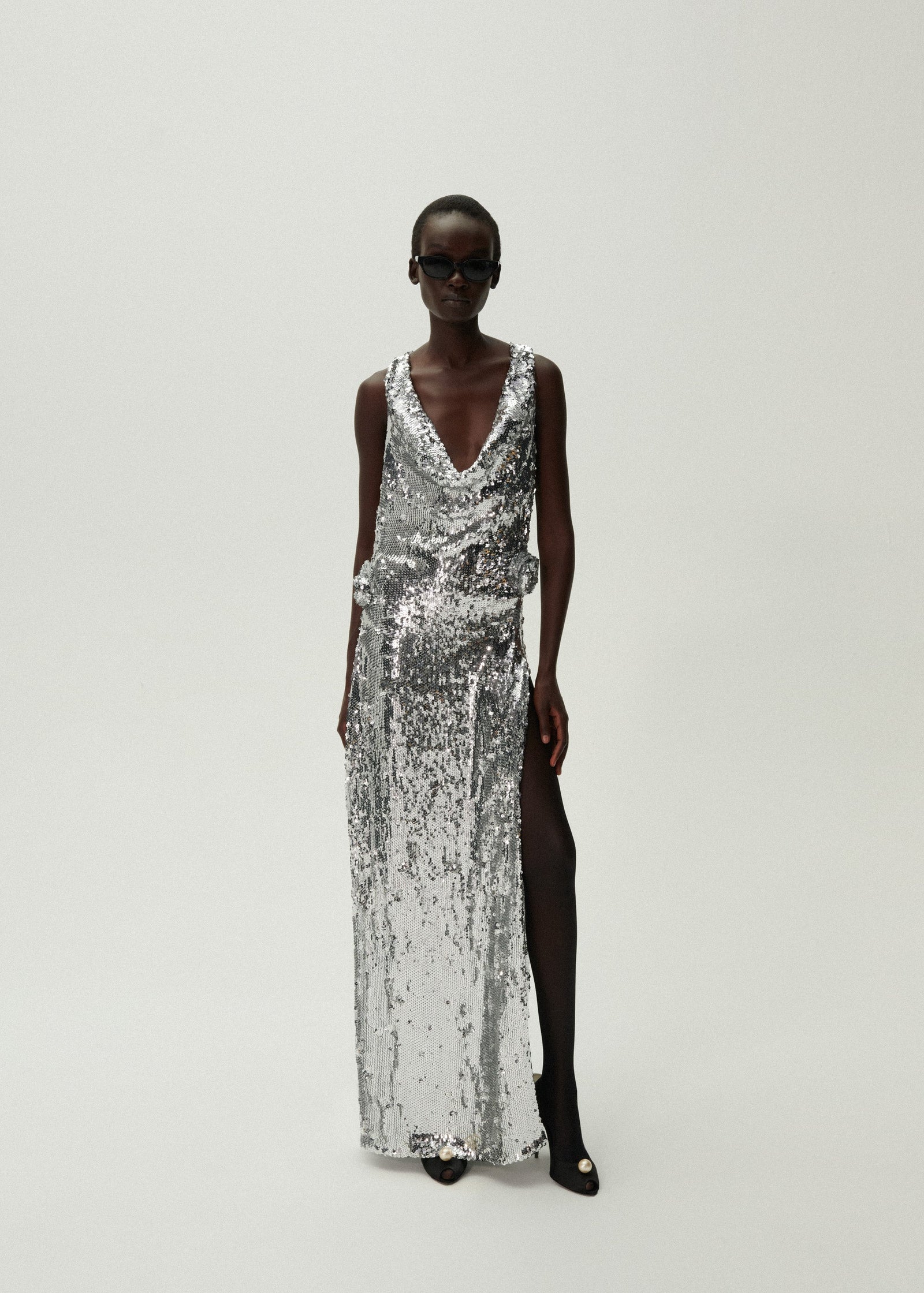 Indulge in luxury with the handnetted sequins and 3D rose appliqué of the Magda Butrym cowl neck dress. Crafted with a plunging neckline and draped back, this silver creation exudes elegance and sophistication. Take center stage and make a statement with this exclusive piece.