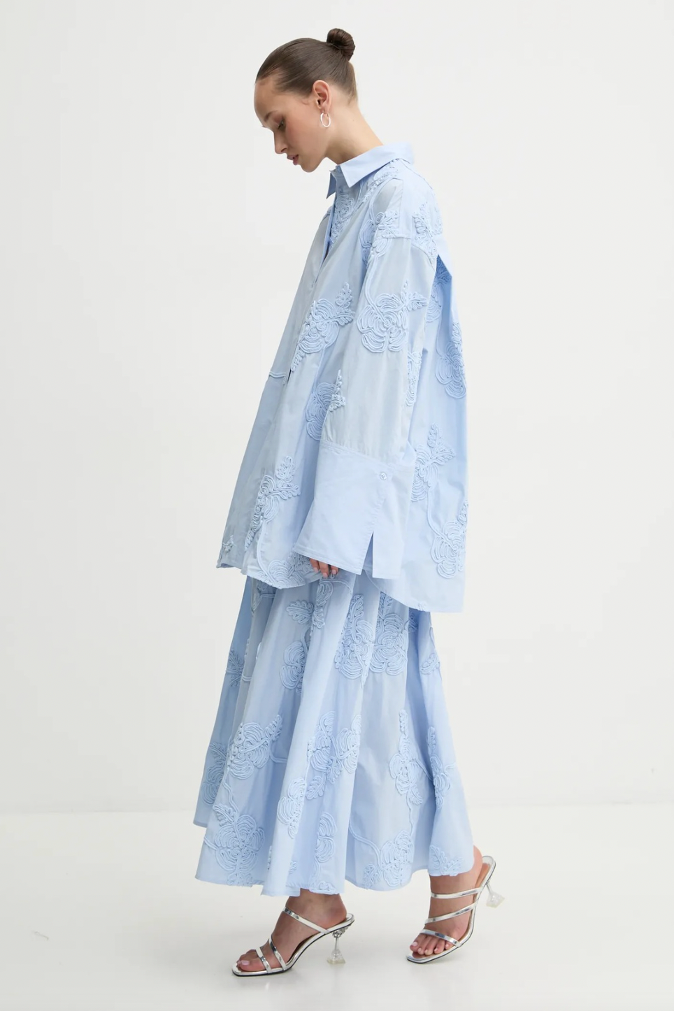 Elevate your style with this high-waisted maxi skirt crafted from sustainable organic cotton. Its flowing, flared design moves gracefully, enhanced by delicate tonal floral embroidery that adds elegant texture. With carefully tailored gathering at the waistband and a hidden side zipper, it offers a flattering fit and lasting comfort. Ideal for sophisticated events, this skirt combines refined elegance with eco-conscious craftsmanship to enhance your wardrobe effortlessly.