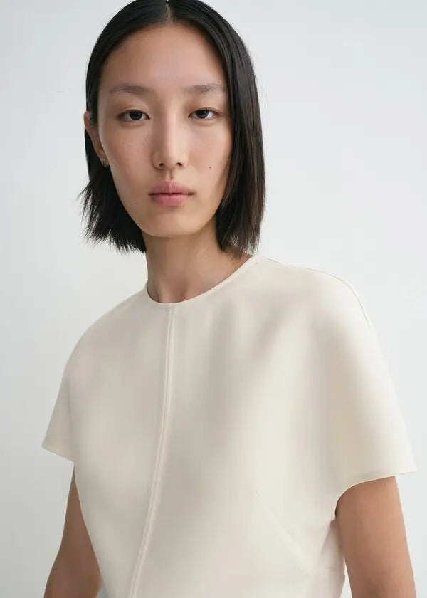 Discover understated luxury with this cap-sleeve top by Toteme, where contemporary design meets timeless sophistication. The elongated cut creates a flattering silhouette while twisted seams introduce subtle architectural detail. Constructed from premium double-faced cady blended with wool and silk, it delivers exceptional comfort without compromising on durability. A hidden back zipper provides a clean, refined finish—perfect for seamless layering or standalone elegance. 