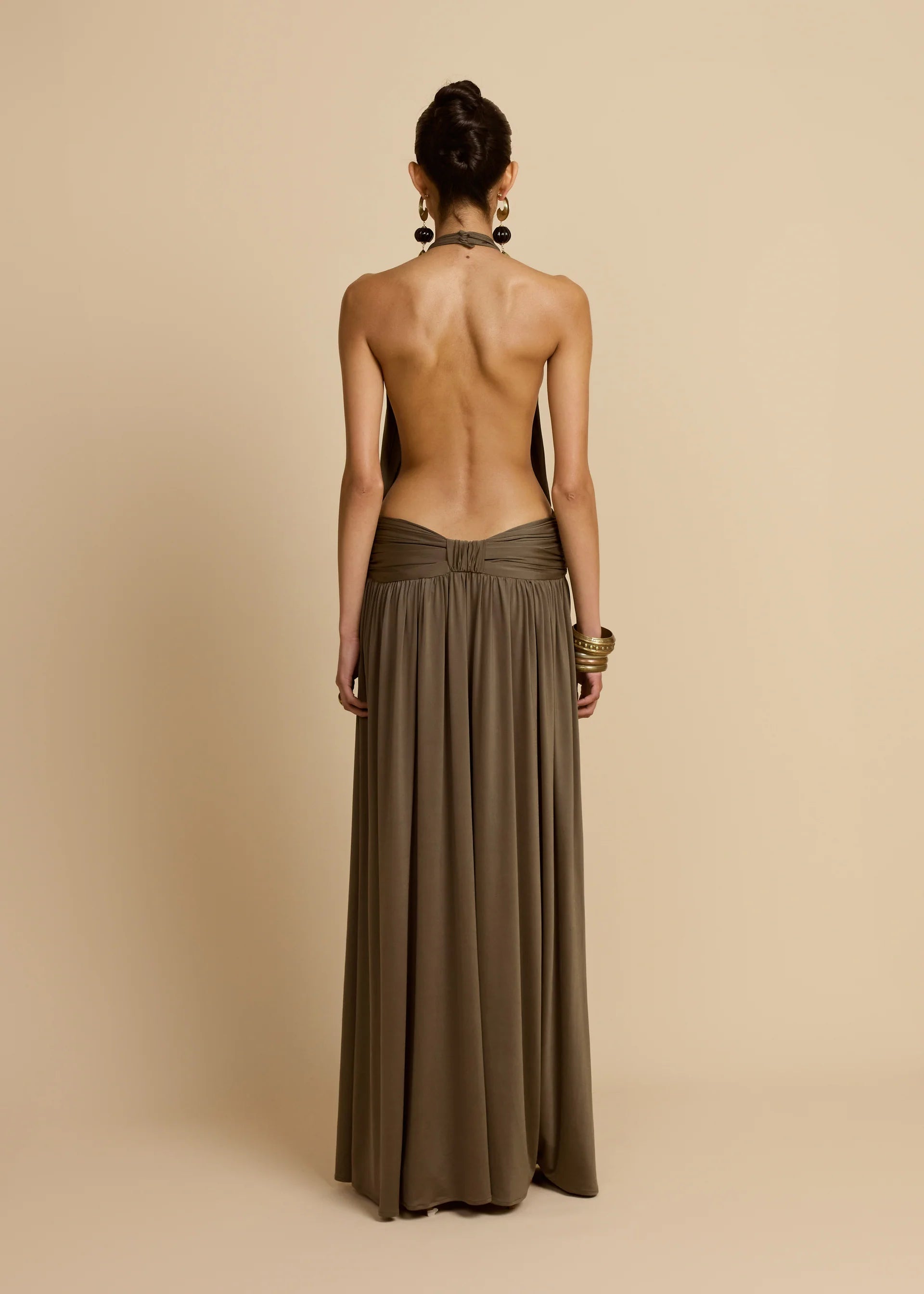 Introducing Santina by Arcina Ori—where sophistication meets movement. This khaki halter dress captivates with its fluid draping and sensual design details, including a ruched centre back and strategically placed gathers that flatter your silhouette. The low-set waistband and floor-length hem create an elongated, graceful line, while the open back design adds an element of allure perfect for making an entrance. 