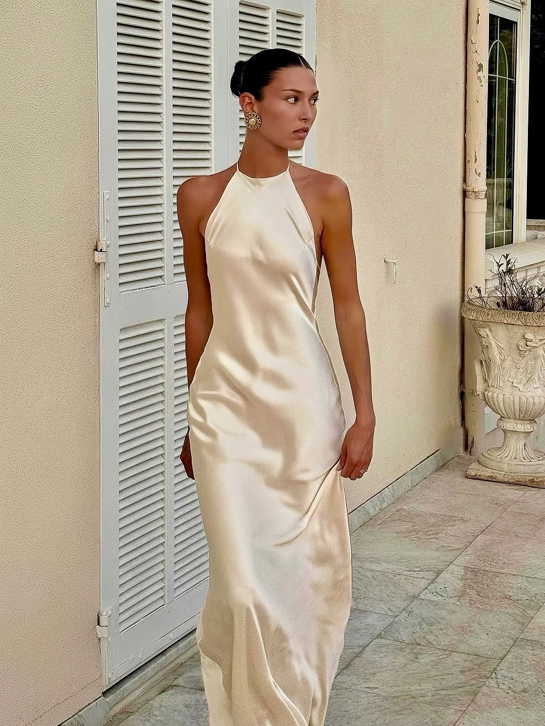 The Jeany Silk Dress delights with adjustable straps and a chic halter neckline, perfectly complemented by elegant back buttons and bias stitching that beautifully drapes your silhouette. Designed to flirt with the floor when paired with heels, it offers a stunningly elongated look—just the right excuse for a little hemming fun! The playful ties at the back ensure a fit as unique as you are, combining charm and comfort for those unforgettable special moments.