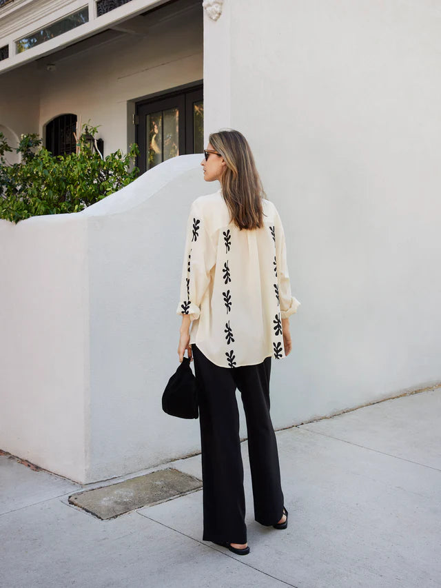 Add a touch of elegance and sustainability to your wardrobe with the Long Sleeve Silk Shirt by Matteau. Made from 100% organic silk with a luxurious crepe finish, this classic button down shirt features a subtle Fig Leaf print, side splits, and a curved hemline. Perfect for any season, this timeless piece will elevate any outfit.