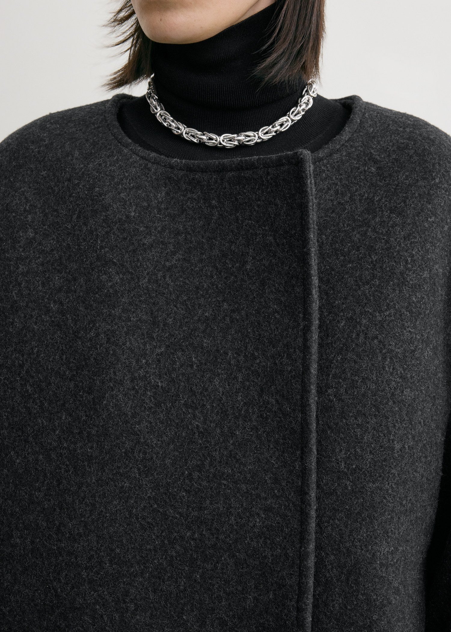Effortless sophistication meets architectural design in this collarless felt coat by Toteme. Crafted from substantial wool-blend felt, its clean lines and drop shoulders create a modern silhouette that drapes like a protective shell around your frame. The buttonless double-breasted front eliminates fussy closures, while jet pockets offer practical elegance. Partial interior lining and an internal pocket balance minimalist aesthetics with everyday functionality. 