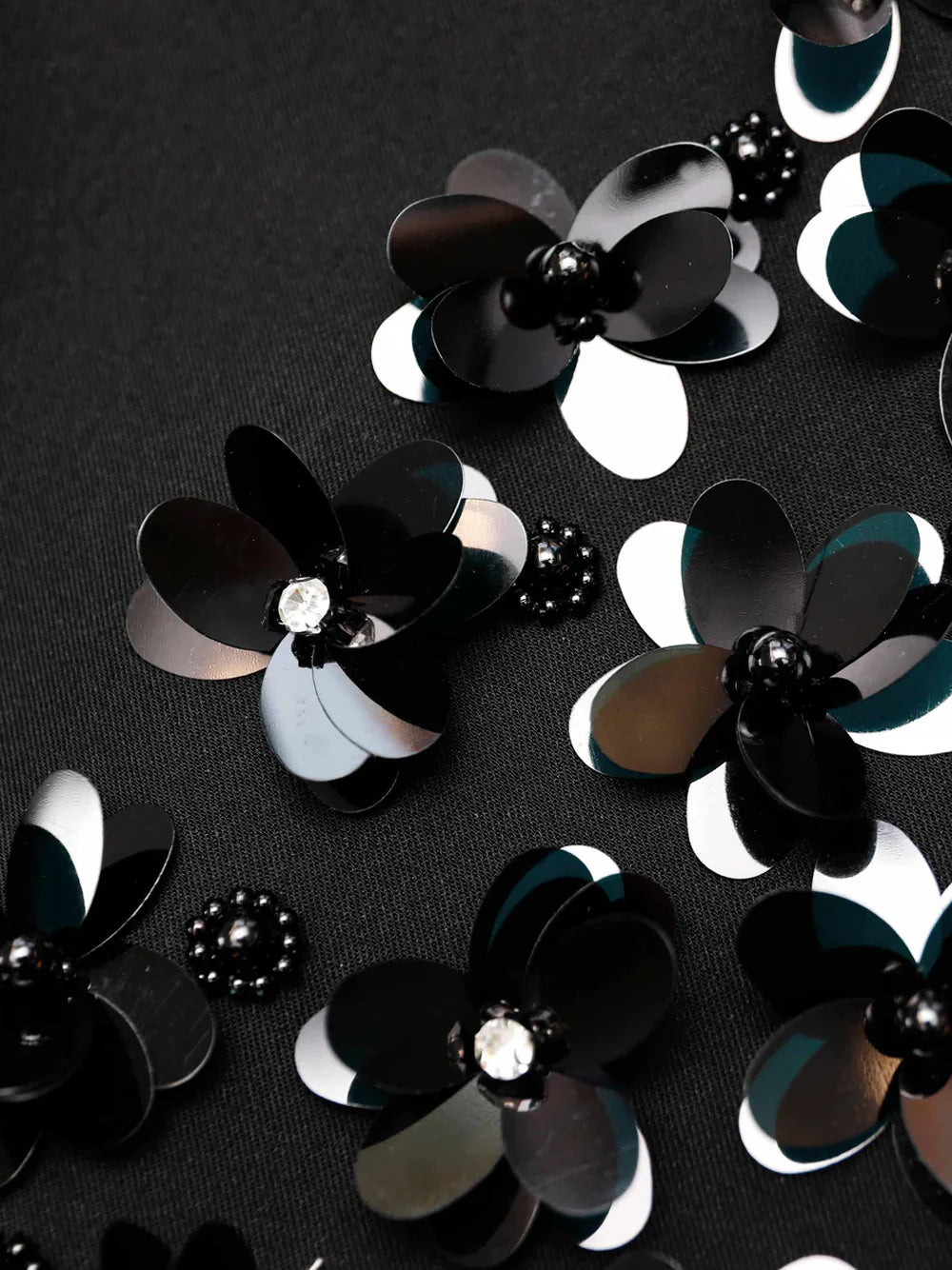 Indulge in ultimate elegance with the Black Crepe Sequin Mini Dress by Self-Potrait. Crafted from the finest bonded crepe, this dress offers a luxurious, smooth finish. The embellished flower hem adds a touch of sophistication, while the plunging V-neckline creates a timeless and glamorous look. Complete your ensemble with statement earrings for the perfect party outfit.