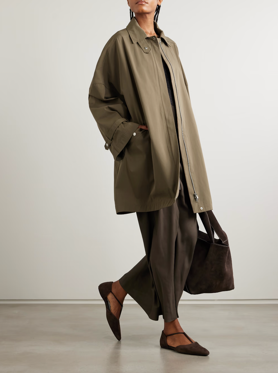 This organic cotton trench coat from TOTEME elevates any outfit with its clean, structured silhouette. Crafted from crisp organic cotton, it offers comfort and sustainability. Its roomy shape ensures ease of movement, while cuff tabs and a throat latch beneath the collar add thoughtful detailing. The partially concealed placket creates a sleek, polished look, making this coat a versatile essential for refined style.
