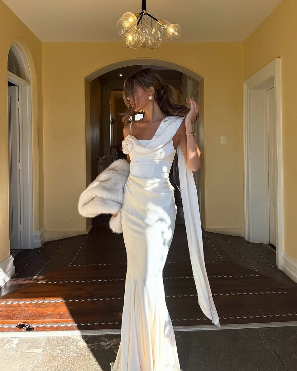 Elevate your elegance with the Celine Corset Gown, a luxurious satin masterpiece designed to flatter every figure. Featuring a corset waist that sculpts your silhouette and graceful draping at the hips, this gown enhances your natural curves. The asymmetric design highlights a delicate rosette on one shoulder and a flowing scarf on the other, adding a unique touch of sophistication. The slightly flared hemline completes this stunning look, perfect for making a memorable entrance at any special occasion.