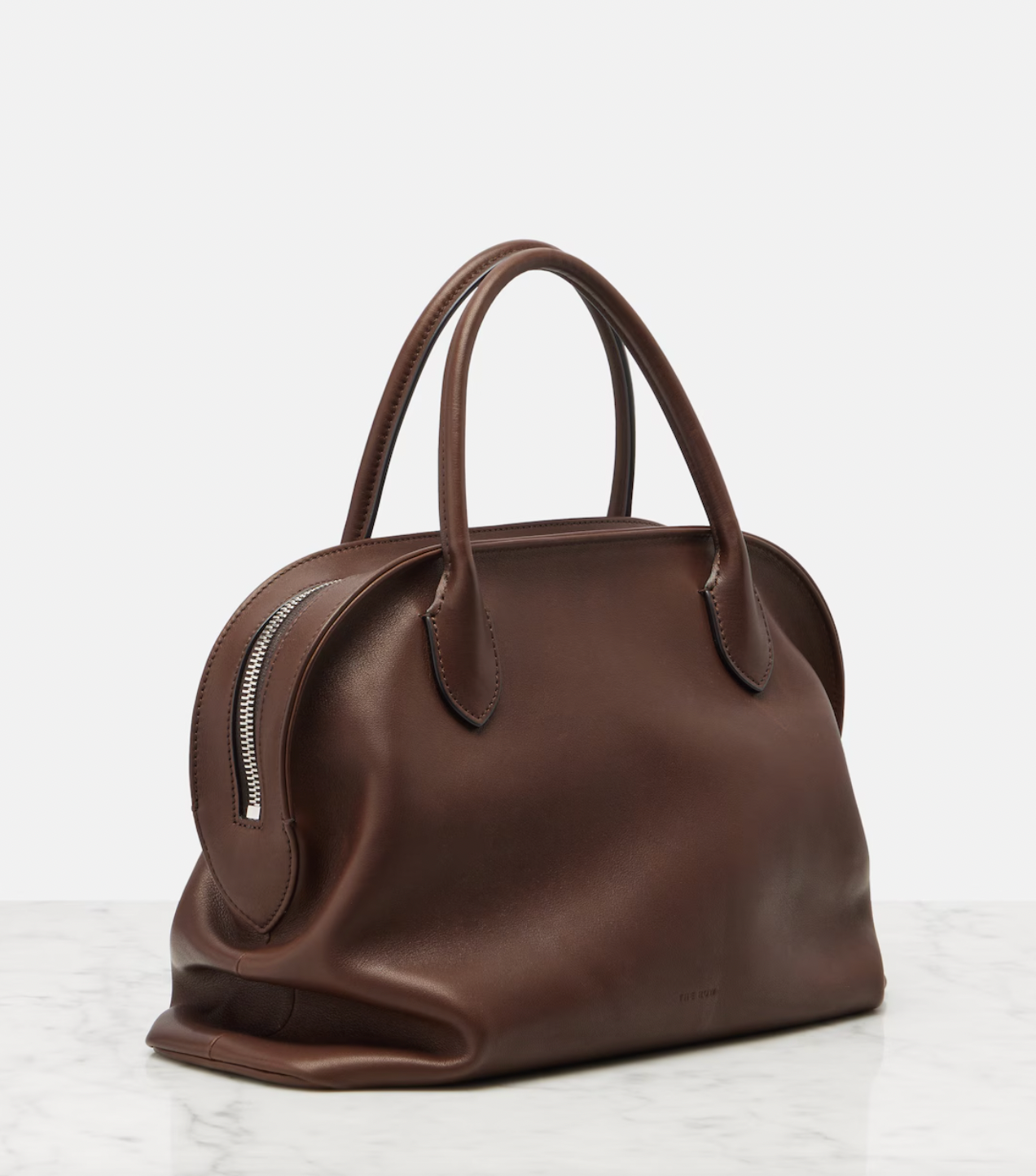 The Agnes tote by The Row combines understated luxury with everyday practicality. Crafted from polished saddle leather, this sophisticated bag features a softly slouched silhouette that moves with you, paired with sturdy tubular handles for effortless carrying. The secure zipper closure keeps your essentials protected while maintaining the bag's refined aesthetic. Perfect for those who appreciate timeless design and quality craftsmanship, the Agnes transitions seamlessly from work to weekend.